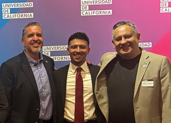 Sergio Maciel and Pablo Reguerin pose with a campus administrator in front of a Universidad de California backdrop.