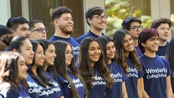 A group of Wonderful Company Scholars pose in matching blue shirts in front of a building.