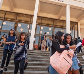 Students exiting the lecture hall building and walking down the steps.